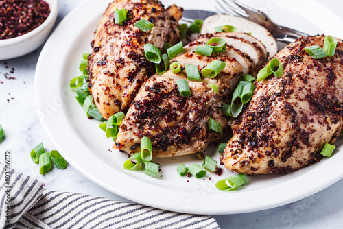 Fried sumak chicken with green onion on white plate.