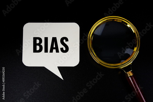 Bias text on speech bluble with magnifying glass top view on blck background