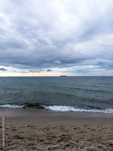 burzowe chmury nad plażą nad morzem Bałtyckim. na horyzoncie widoczny statek transportowy