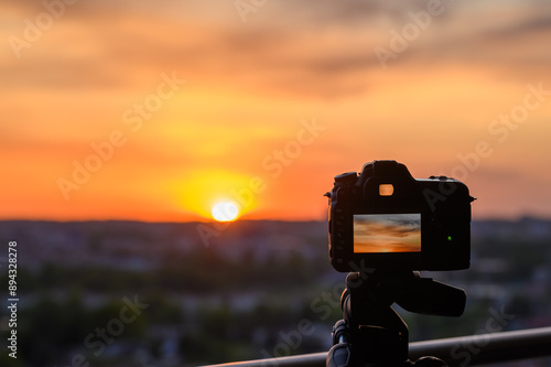 Aparat fotograficzny ustawiony na statywie w stronę zachodzącego słońca, złota godzina 