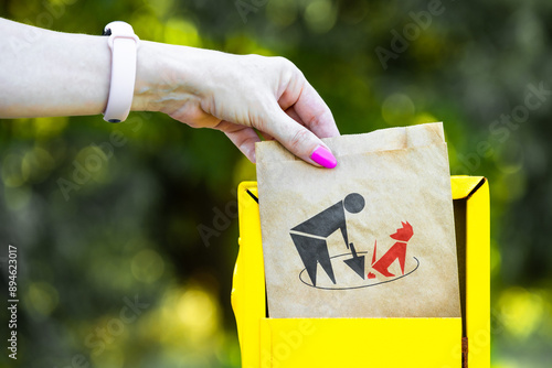 hand takes out a paper bag for dog excrement from a box in the park. female hand holding dog waste bag. paper bag for dog excrement. dog park area. close-up photo