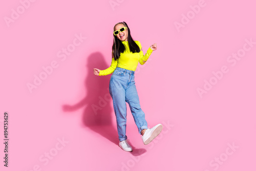 Full size photo of good mood girl with dyed hair dressed yellow shirt jeans in sunglass dancing at party isolated on pink color background