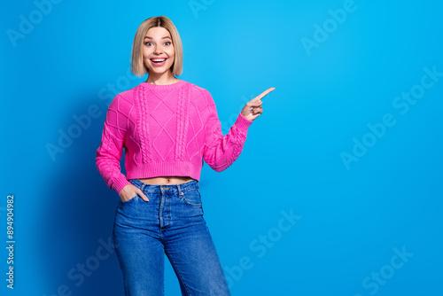 Portrait of nice young woman indicate finger empty space wear pink sweater isolated on blue color background