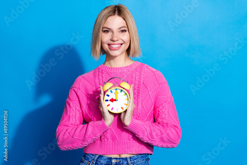 Portrait of nice young woman hold alarm clock wear pink sweater isolated on blue color background