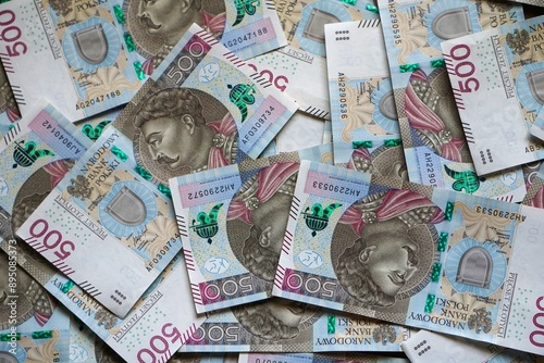 Banknoty o nominale 500 zł porozrzucane na ziemi. Liczne banknoty widoczne z bliskiej odległości. Polska waluta fiducjarna o wysokim nominale. Pieniądze używane w Rzeczpospolitej.