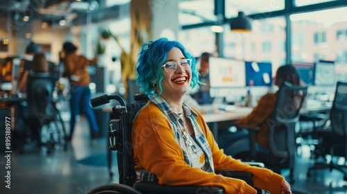 Cheerful woman in wheelchair with blue hair smiling in modern office