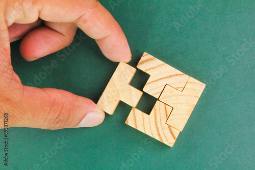 hands complete a wooden puzzle. last missing piece, solutions and challenges concept 