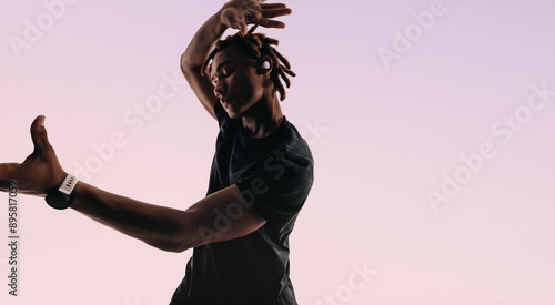 Expressive dance moves: Young man dancing to the rhythm with wireless earphones in studio