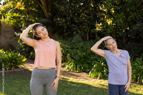 Exercising in park, asian grandmother and granddaughter stretching neck muscles outdoors together