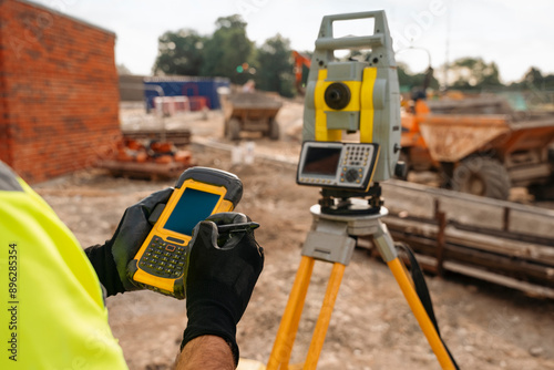 Construction Worker Using Surveying Equipment and Data Collector