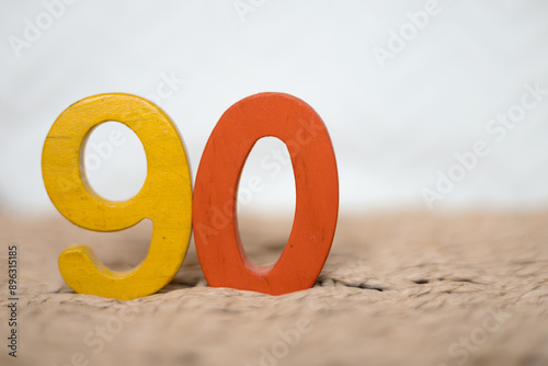 Close-up wooden figure number ninety on a white blurred background