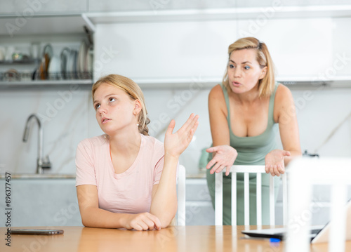 Offended frustrated teenage girl making dismissive hand gesture forced to listen to reprimands of disgruntled mother. Concept of disagreement between children and parents