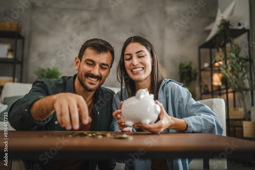 Adult couple save money coins in the piggy bank at home