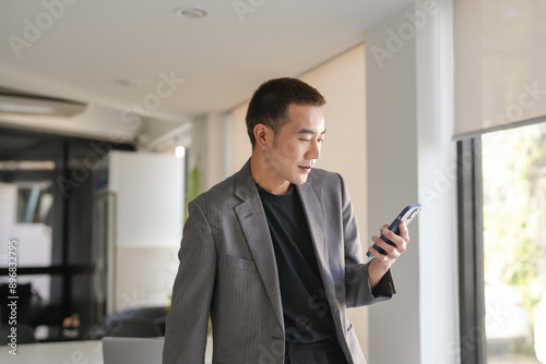 Smiling confident asian Business man using smartphone mobile addict spending time checking news technology e-commerce concept.