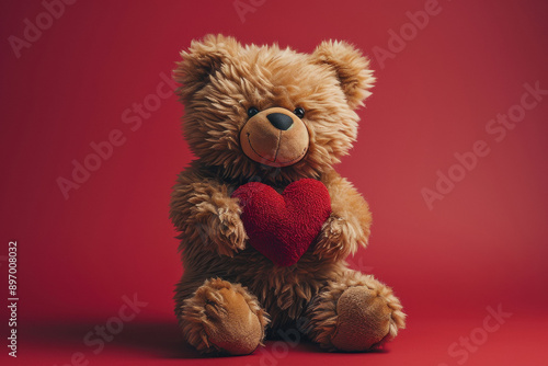 a cute teddy bear holding a red love heart, studio shot against a red background