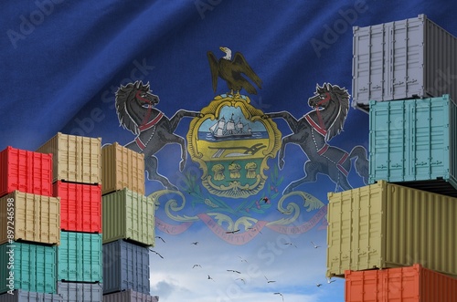 Pennsylvania US state flag and big stack of shipping cargo containers in docks with sky background close up