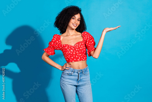 Portrait of gorgeous young woman hold empty space ad wear top isolated on blue color background