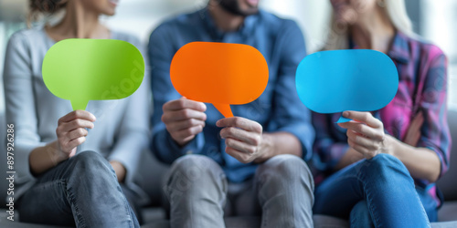 Group of three people holding vibrant, colorful speech bubbles, representing communication, discussion, and dialogue in a casual setting.