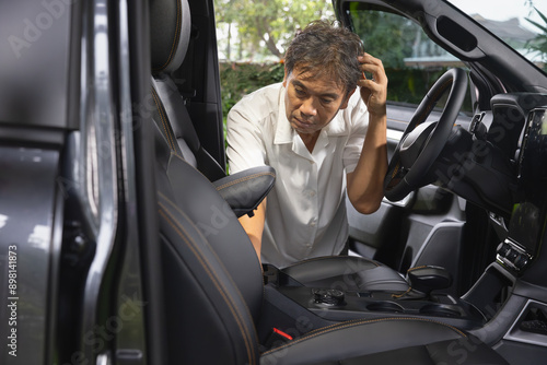 Senior asian man loking for the forgot key inside car.