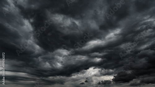 dark dramatic sky with black stormy clouds before rain or snow as abstract background, extreme weather, the sun shines through the clouds, high contrast photo