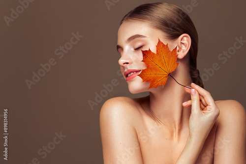 Portrait of beautiful young woman with autumn leafs. Healthy clean fresh skin natural make up beauty eyes