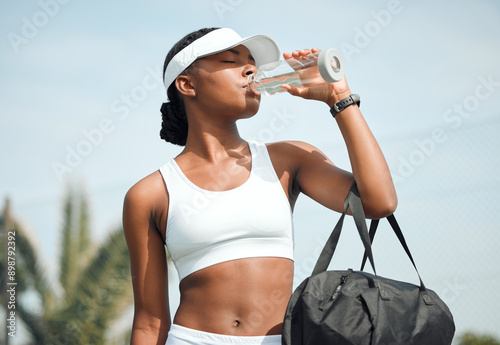 Tennis, drinking water and black woman on court, sports and fitness with nutrition, wellness and workout. African person, outdoor and athlete with bottle racket and training with break and healthy