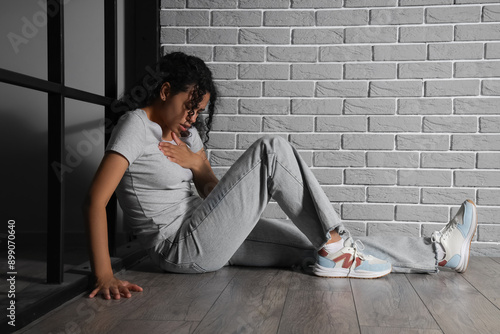 Young African-American woman having panic attack in room