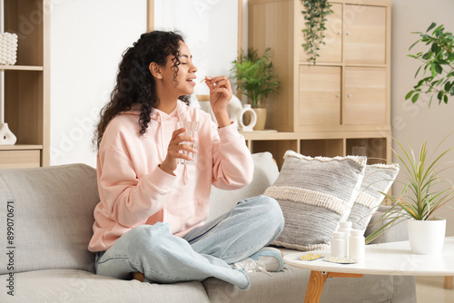 Young African-American woman taking fish oil at home