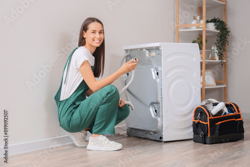 Female plumber fixing washing machine in bathroom