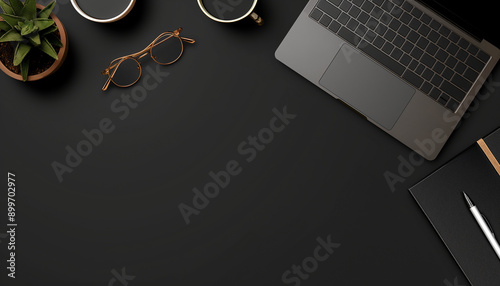 A modern workspace featuring a laptop, glasses, coffee cups, and a small potted plant on a black desk.