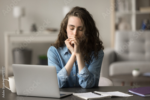 Young woman sits at desk with eyes closed, think on project, search solution or ideas, stuck with hard task. Student resting seated at table, take break, relieving fatigue feel drained and unmotivated