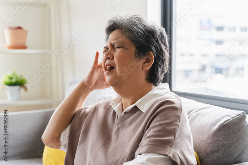 Elderly women feeling dizzy and headache sit on the sofa at home.