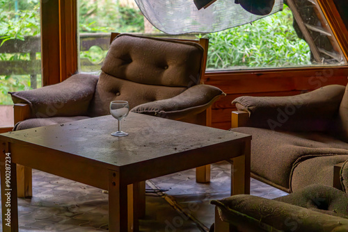 Destroyed furniture in an abandoned recreation center, old armchairs, a table and a glass on it