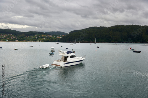 small pleasure yacht with inflatable boat tied to the bow in Cedeira Bay