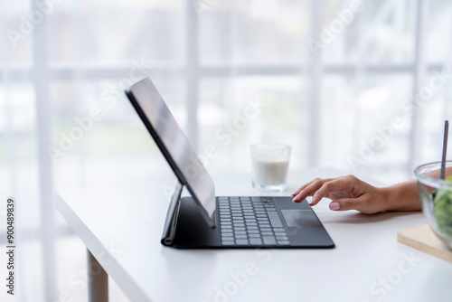 Woman working from home using tablet with keyboard and trackpad