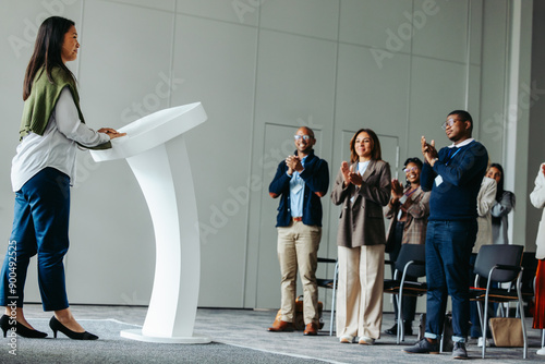 Female leader giving a business presentation at a conference event, receiving applause from the audience