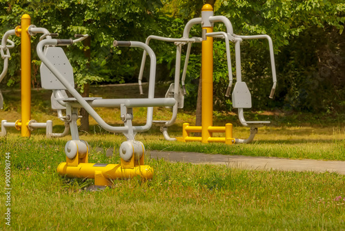 Park miejski - siłownia na świeżym powietrzu na pierwszym planie "wioślarz". Sprzęt do ćwiczeń na świeżym powietrzu w parku miejskim w letni dzień. 