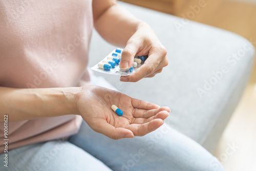 Sick, ill asian young woman, girl hand holding and taking tablet pill capsule, painkiller medicine from stomach pain, head ache, pain for treatment, take drug or vitamin at home, health care concept.