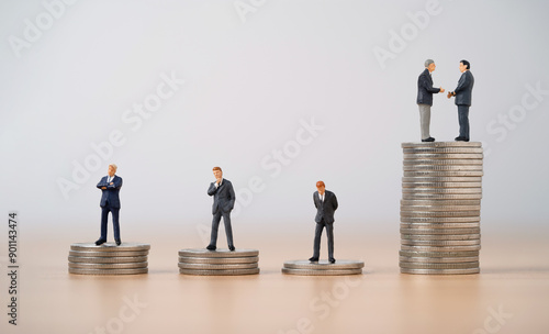 Two businessmen miniature figure hand shaking among businessmen individual standing on coins stacking for business corporate can make more benefit and profit concept.