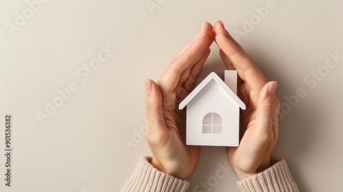 Hands encircling a model house, depicting the security and protection of home insurance