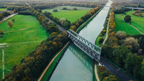 Autumn aerial drone view landscape navigable river with bridges, agricultural fields and forests and farmers houses in Germany countryside.