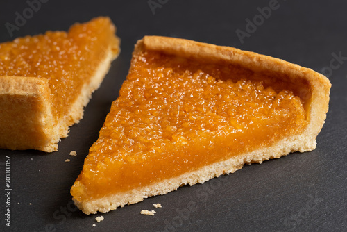 Two portions of treacle tart on black slate.