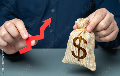 Businessman holding dollar money bag and red arrow of growth. Achieving a high return on investment signifies successful financial endeavors. Rising interest rates. Growth of profits and income.