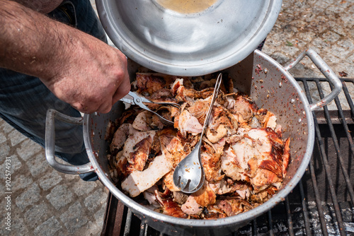 Panela com carne de porco no espeto fatiado pronto para fazer sandes num evento ao ar livre