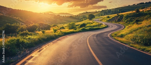 Scenic road trip through nature. Asphalt highway winds picturesque landscape surrounded by lush greenery and rolling hills. Warm tones of sunset cast golden glow over scene creating serene