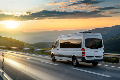 White minibus driving on a scenic highway during sunset, showcasing intercity public transportation in a mountainous landscape.