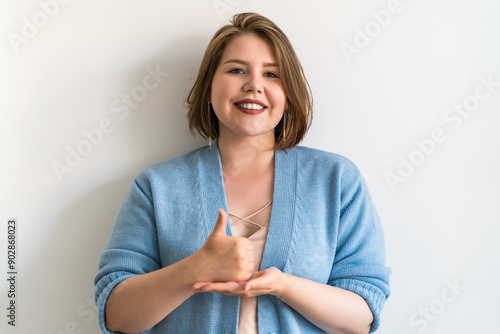 Plus size woman showing thumbs up sign in sign language, expressing approval and positivity. Concepts of inclusivity, communication, and positive feedback.