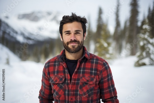 Portrait of a glad man in his 30s wearing a comfy flannel shirt isolated on pristine snowy mountain