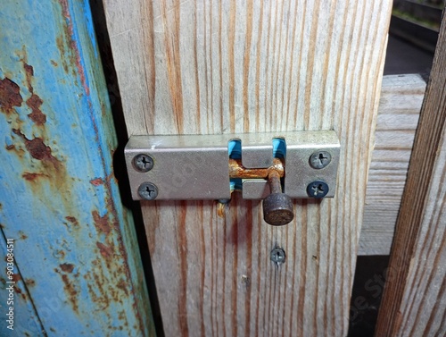 A metal hinge on an old wooden door is fixed with metal screws. Metal lock on a wooden old door.