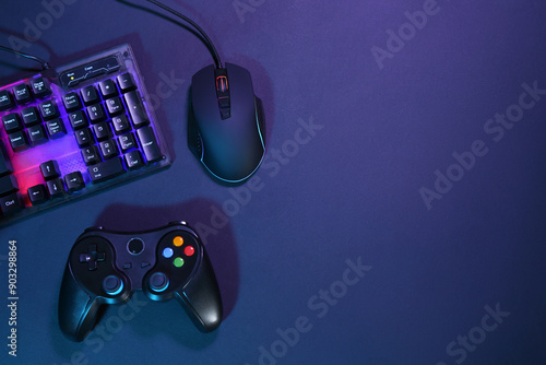 Computer mouse, RGB keyboard and game controller on dark background, flat lay. Space for text